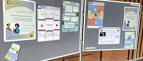 Zwei Stellwände im Gang der Philosophischen Fakultät. Daran hängen vier Poster, auf denen jeglicher Text fehlt. Darüber ist mit Edding geschrieben: "Was entsteht hier? Komm zur Posterpräsentation"