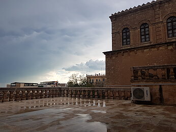 Eine dunkle Regenwolke hinter einem reichverzierten Altbau. 
