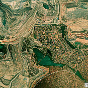 Das optische Satellitenbild zeigt ein Minenareal (links) in Kolwezi, wo Siedlungsstrukturen bis an den Minenrand heranreichen.